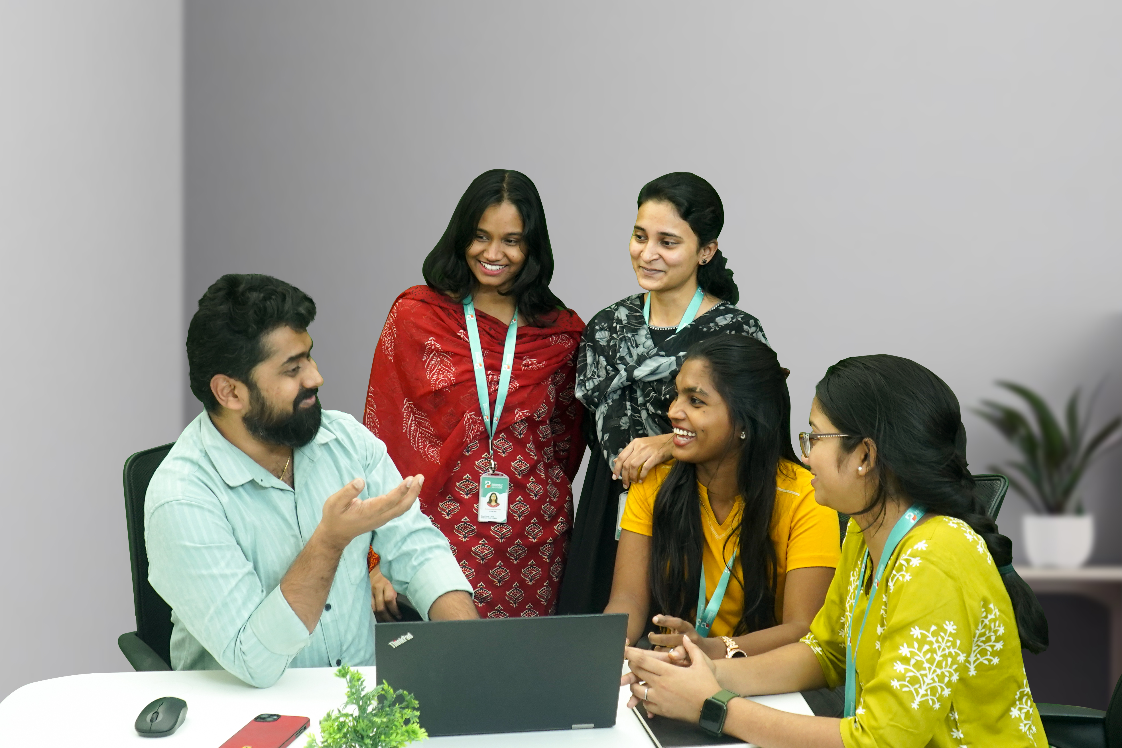 A group of people working together in an office setting, with one person smiling at the camera